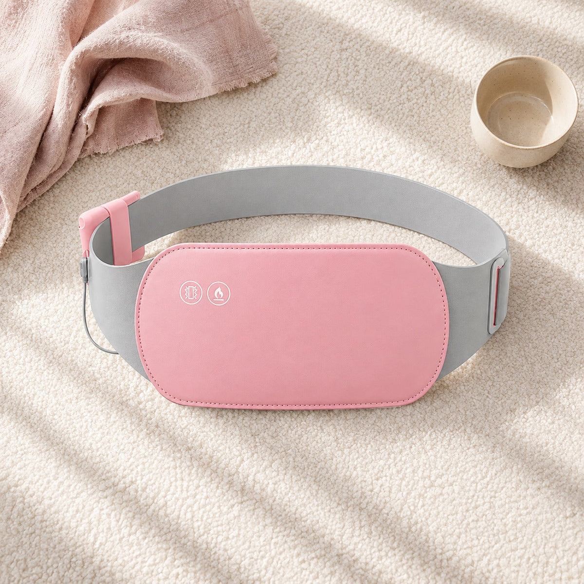 Ceinture chauffante Belyss posee sur un plaid rose avec une tasse